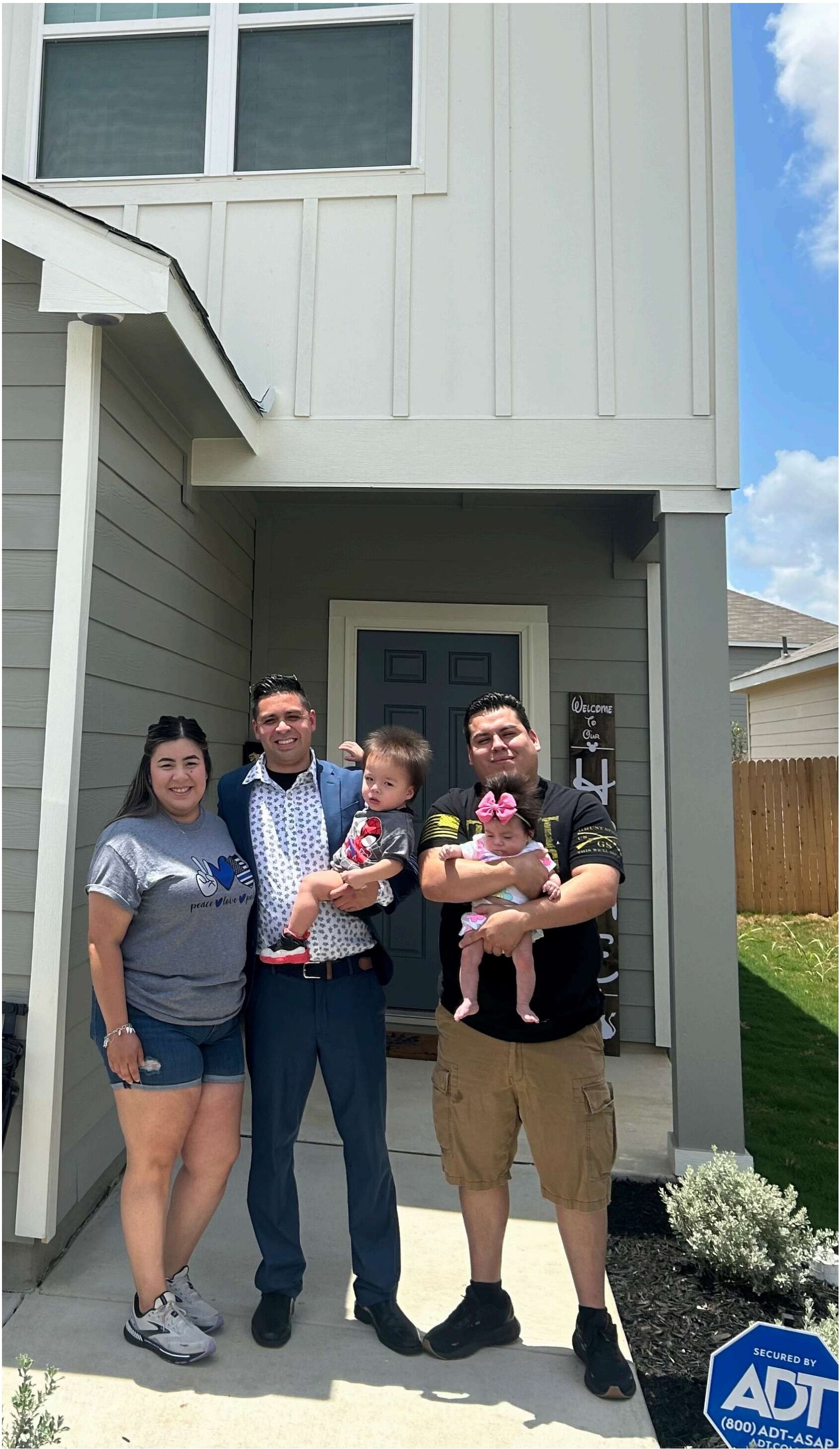 Family in front of their new home with a Welcome To Our Home sign